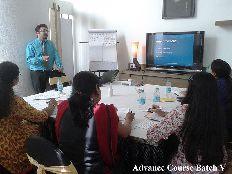 Group of people in a classroom setting with a presenter and a screen displaying 'Laser Techniques'.