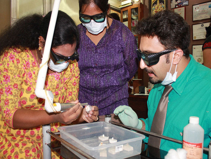 Group of people in a laboratory setting with protective gear, focusing on an experiment.